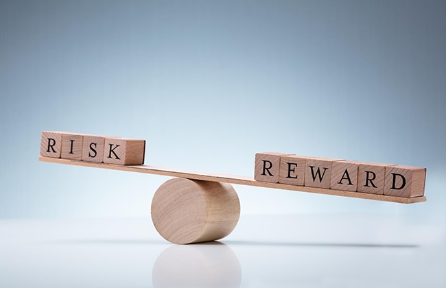The words Risk and Reward on opposite sides of a balance board