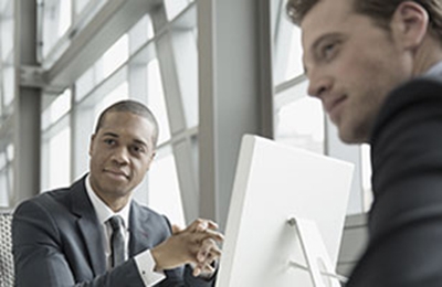 Two employees sit at a desk collaborating. 