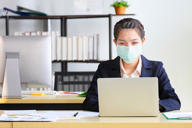 Woman working on computer wearing a mask